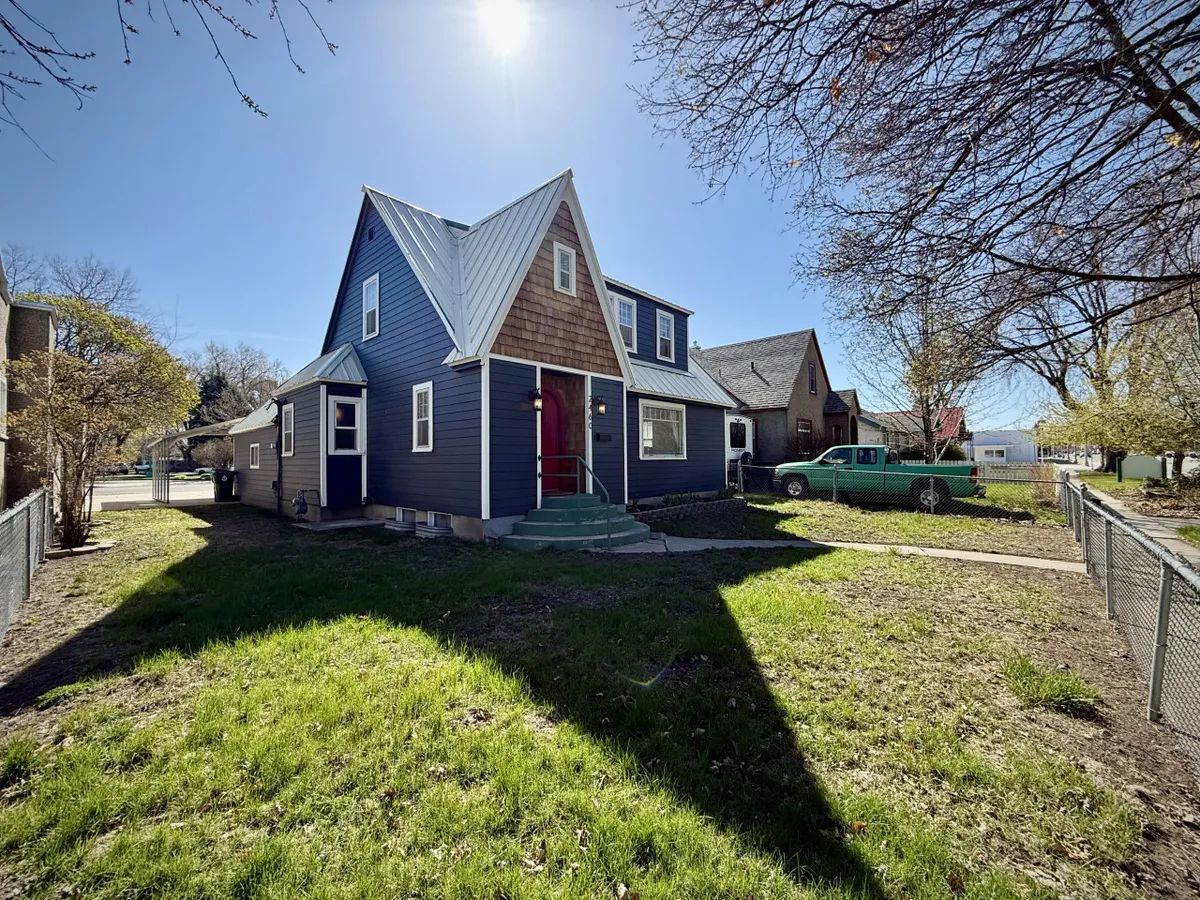 This exterior shot shows a unique A-frame house with a brightly painted blue exterior and a cheerful red front door. The yard appears welcoming and family-friendly, ideal for gatherings or children's play. The scene evokes an inviting, homey atmosphere that matches the playful and communal spirit described in the section.