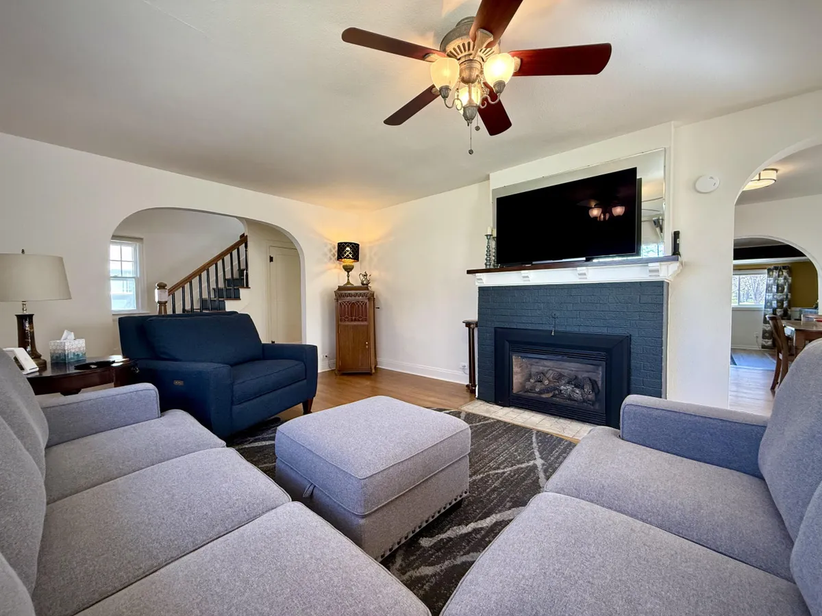 A cozy interior living room featuring a comfortable sofa, fireplace, television, lamp, and staircase. The room radiates warmth and relaxation, suggesting a perfect spot to unwind with your pet after a day outdoors.