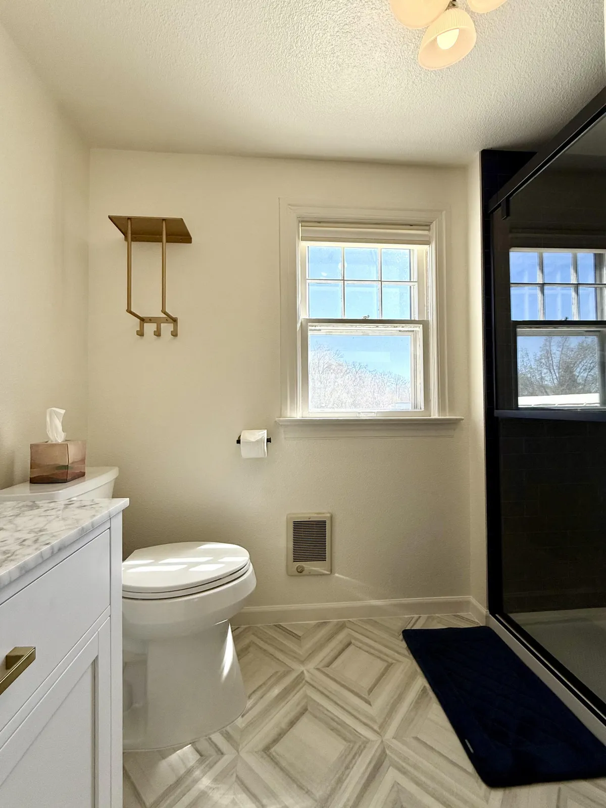 This inviting bathroom features a clean layout with a shower, toilet, vanity, and a window that brings in fresh, natural light. The design is both practical and welcoming, suggesting a space well-suited for relaxation and privacy.